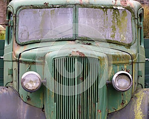 Front view of an old abandoned green rusty 1940s truck