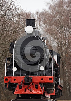 Front view of old classic black steam locomotive with red decoration