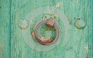 Front view of old doorknocker and green painted wooden door