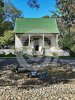 Front view of old farm equipment and little wooden cottage at the Coblestone Settlers Museum in Greytown Wairarapa New Zealand