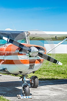 Front view of old red and white single engine propeller plane on grass field.