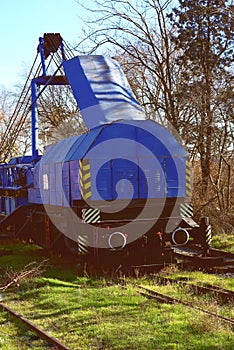 Front view, of an old train with a locomotive and track overgrown