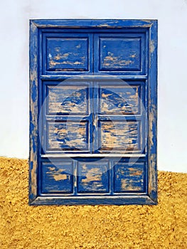 Front view of old wooden sash window painted blue on cement facade. Blue closed rustic window. Urban Planning and Constructions