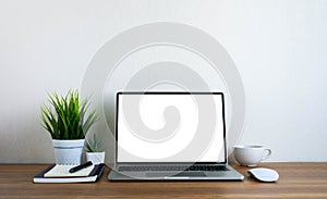 Front view of open laptop computer notebook with blank monitor white screen display on work table desk.