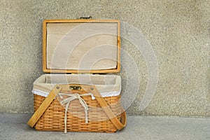 Front view open weave wooden basket and white fabric on cement background, object, copy space