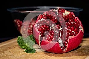 Front view of opened pomegranate with mint leaves and bawl of seeds