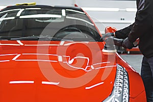 front view of an orange car being polished by a professional mechanic at the repair shop