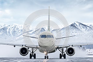 Front view of the passenger aircraft taxiing on taxiway on the background of high snow capped mountains