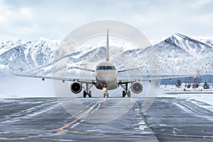 Front view of the passenger airplane taxiing on taxiway on the background of high picturesque mountains