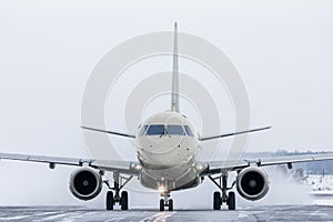 Front view of the passenger jetliner taxiing on taxiway in snowy winter day