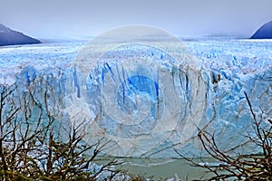 Front view of Perito Moreno Glacier, in El Calafate, Argentina, against a grey and cloudy sky.