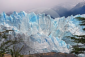 Front view of Perito Moreno Glacier, in El Calafate, Argentina, against a grey and cloudy sky.