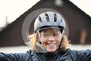 A front view portrait of cheerful active senior woman standing outdoors.