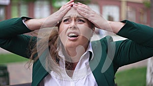 Front view portrait exhausted stressed Caucasian obese businesswoman holding head in hands outdoors. Overburdened