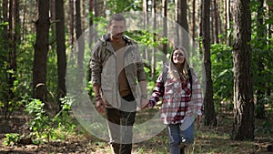 Front view portrait of happy loving couple holding hands walking in slow motion in forest. Smiling Caucasian man and