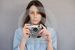 Front view of portrait of nice and young woman holding a vintage style camera
