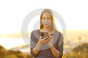Woman using smart phone on the outskirts at sunset photo