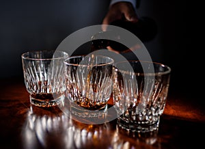 Front view of Pouring strong alcohol drink into the clean glasses