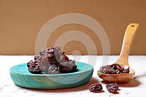 Front view of raisins on plate and wooden spoon photo