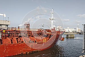 Front view of a red oil tanker sailing through a canal