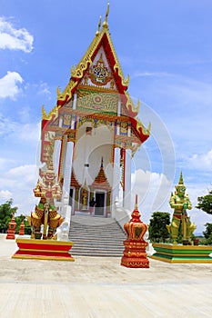 Front view of the red and white temple with the guards and steps leading to the main idol inside at Buang Sam Phan, Phetchabun