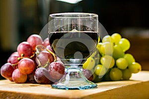 Front view of a red and yellow muscat colored grape and a glass of wine on a wooden board - still life