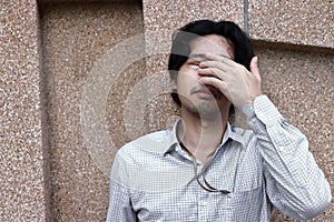 Front view of sad depressed young Asian business man covering face and cry