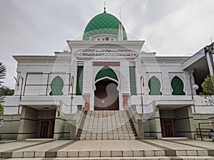 Front view scape of mosque building with green doom