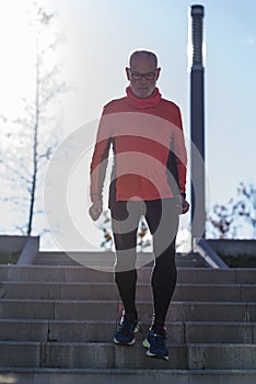 Front view of a senior caucasian athlete man training running up and down the stairs outdoors in a park in a sunny day