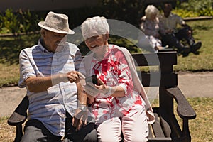 Front view of senior couple discussing over mobile phone in garden