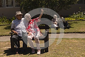 Front view of senior couple taking selfie with mobile phone in garden