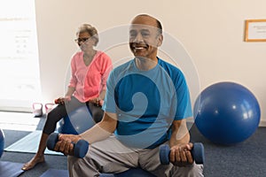Front view of senior man exercising with dumbbells in fitness studio