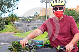 Front view of senior man riding with bicycle in the city, wearing surgical mask due to coronavirus