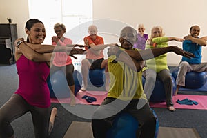 Front view of senior people exercising with female trainer