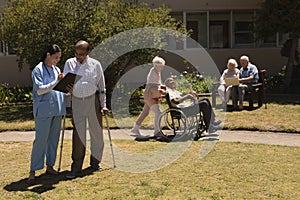 Front view of senior people and female doctor in garden