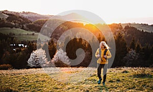 Front view of senior woman hiker walking outdoors in nature at sunset. photo