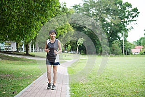 Front view of senior woman jogging through park