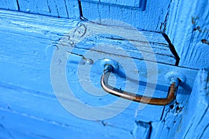 Front view of shiny steel metal old rusty door handle, blue keyhole