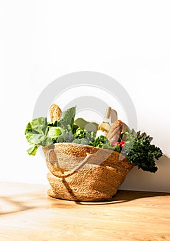 Front view of shopping straw bag full of fresh leafy vegetables. Healthy food ingredients shopping concept