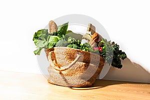 Front view of shopping straw bag full of fresh leafy vegetables. Healthy food ingredients shopping concept