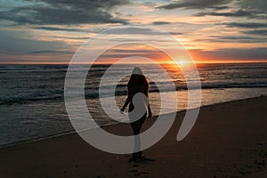 Front view silhouette of attractive woman. Beautiful young girl with long hair walking on the beach, posing at sunset