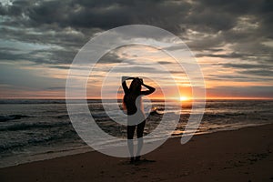 Front view silhouette of attractive woman. Beautiful young girl with long hair walking on the beach, posing at sunset