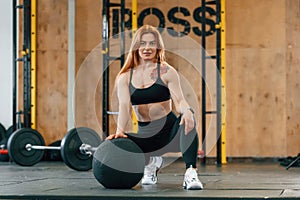 Front view. Sitting, barbell on the floor. Beautiful strong woman is in the gym