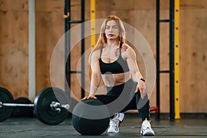 Front view. Sitting, barbell on the floor. Beautiful strong woman is in the gym