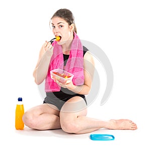 Front view of sitting woman with purple towel eating fresh fruits