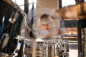 Front view of small boy indoors at home, playing drums.