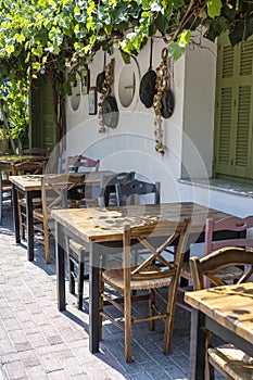 Front view of small cafe exterior. Table and empty chairs outdoor near the white wall. Tourist places. Typical Mediterranean