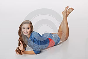 Front view of smiling beautiful woman lying on the floor over gr