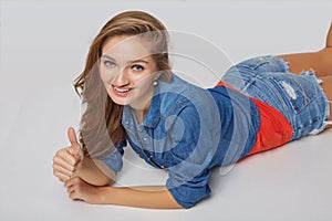 Front view of smiling beautiful woman lying on the floor over gr