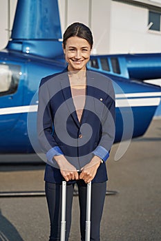 Cheerful lady standing near helicopter on helipad photo